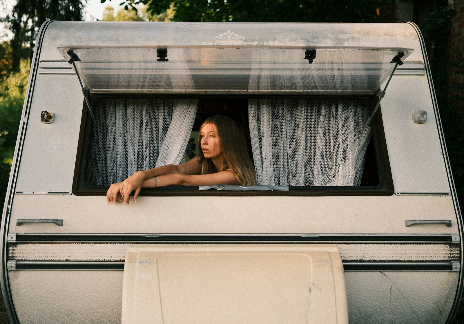 Donna appoggiata alla finestra a compasso aperta di un camper